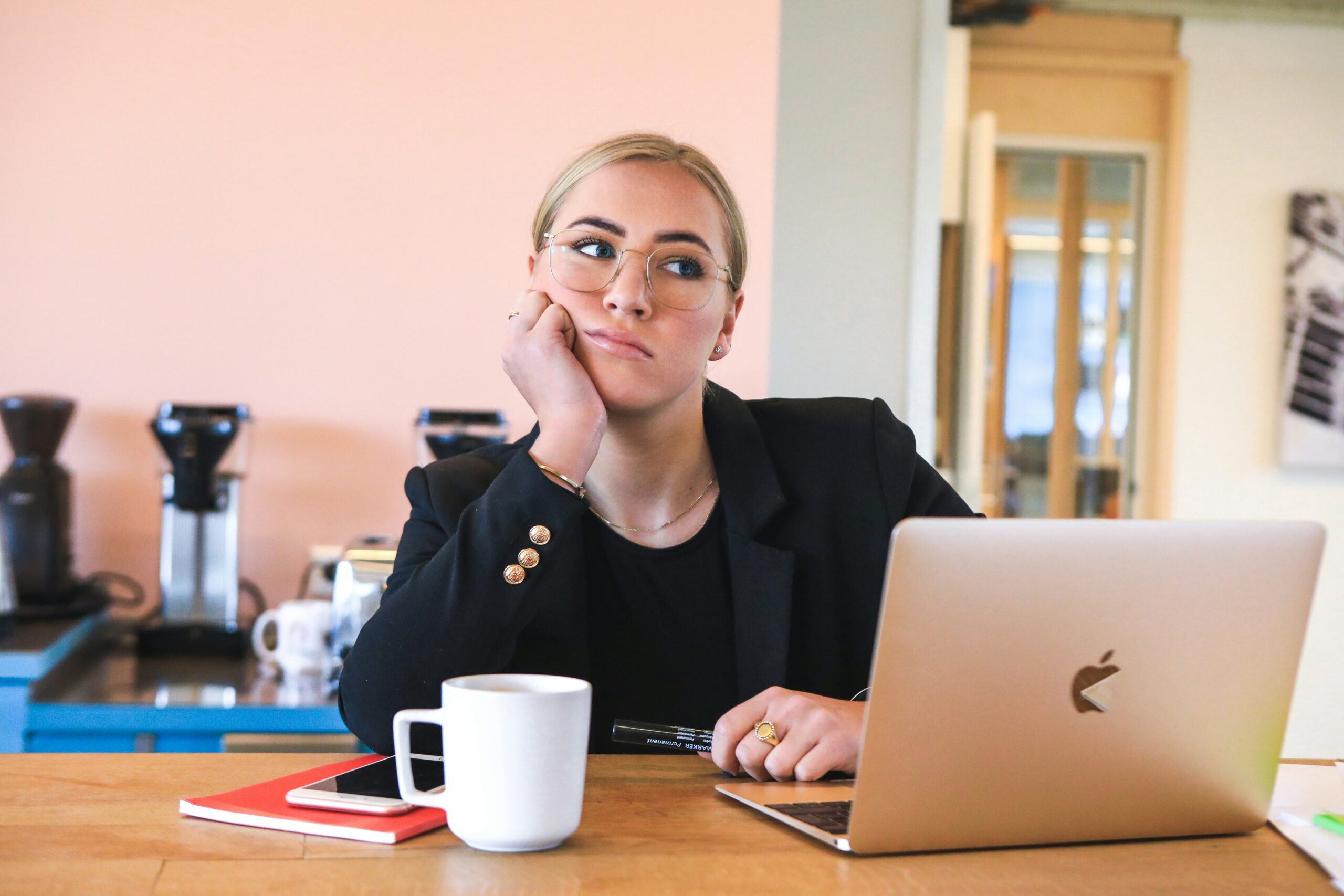 Moça pensativa na mesa de trabalho com macbook